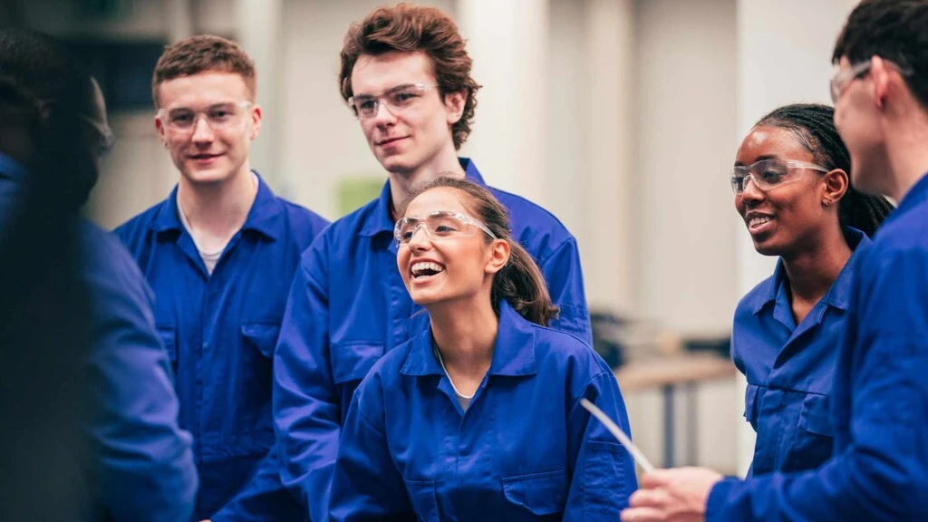 Gruppe junger Menschen in blauer Arbeitskleidung, die miteinander lachen