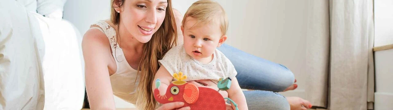 Gesundes Wohnklima: Mutter spielt mit Kind auf dem Boden mit einem roten Elefanten