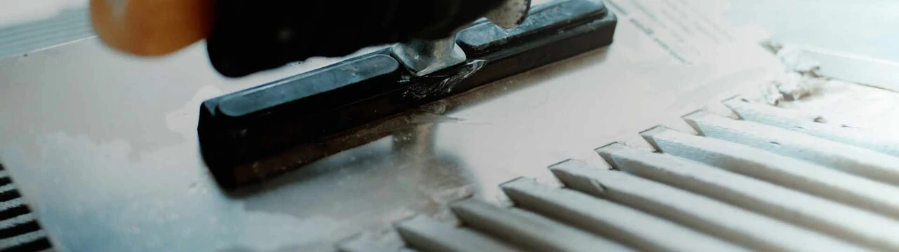 Nahaufnahme der Verarbeitung des BlueComfort Fliesenklebers weber.xerm 842 mit einer Zahnkelle