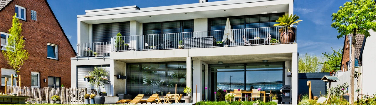 Rückwärtige Ansicht eines Wohngebäudes mit großen Fensterfronten und Edelkratzputz-Fassaden dazwischen