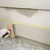 Sockel wird mit einer Fassadenbürste gestrichen