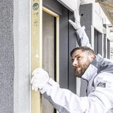 Handwerker prüft die Ausrichtung der weber.projekt WDVS Fertigzarge für den Holzbau mit einer Wasserwage nach dem Einbau