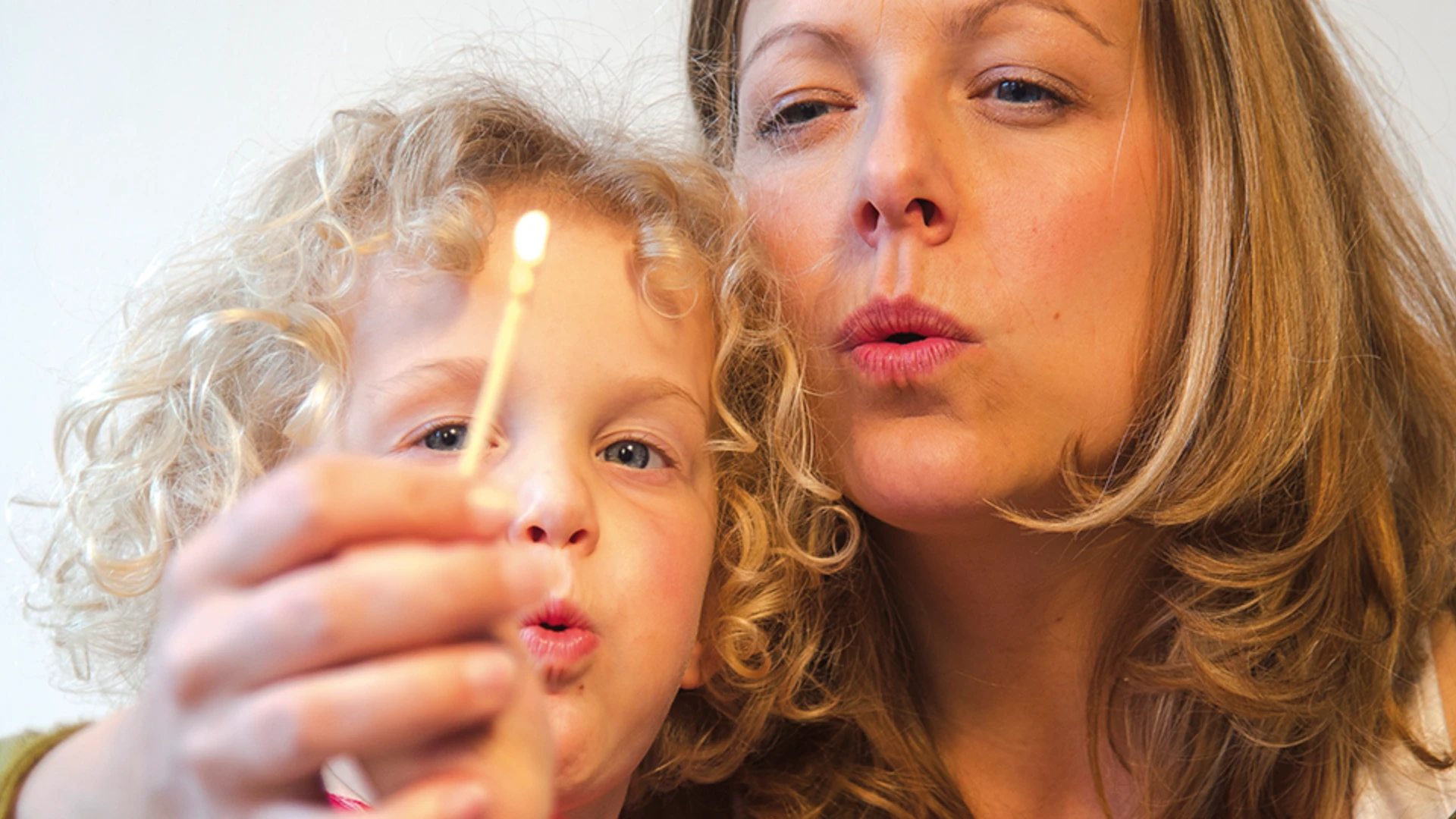 Nahaufnahme einer Mutter, die mit ihrem Kind ein Streichholz auspustet