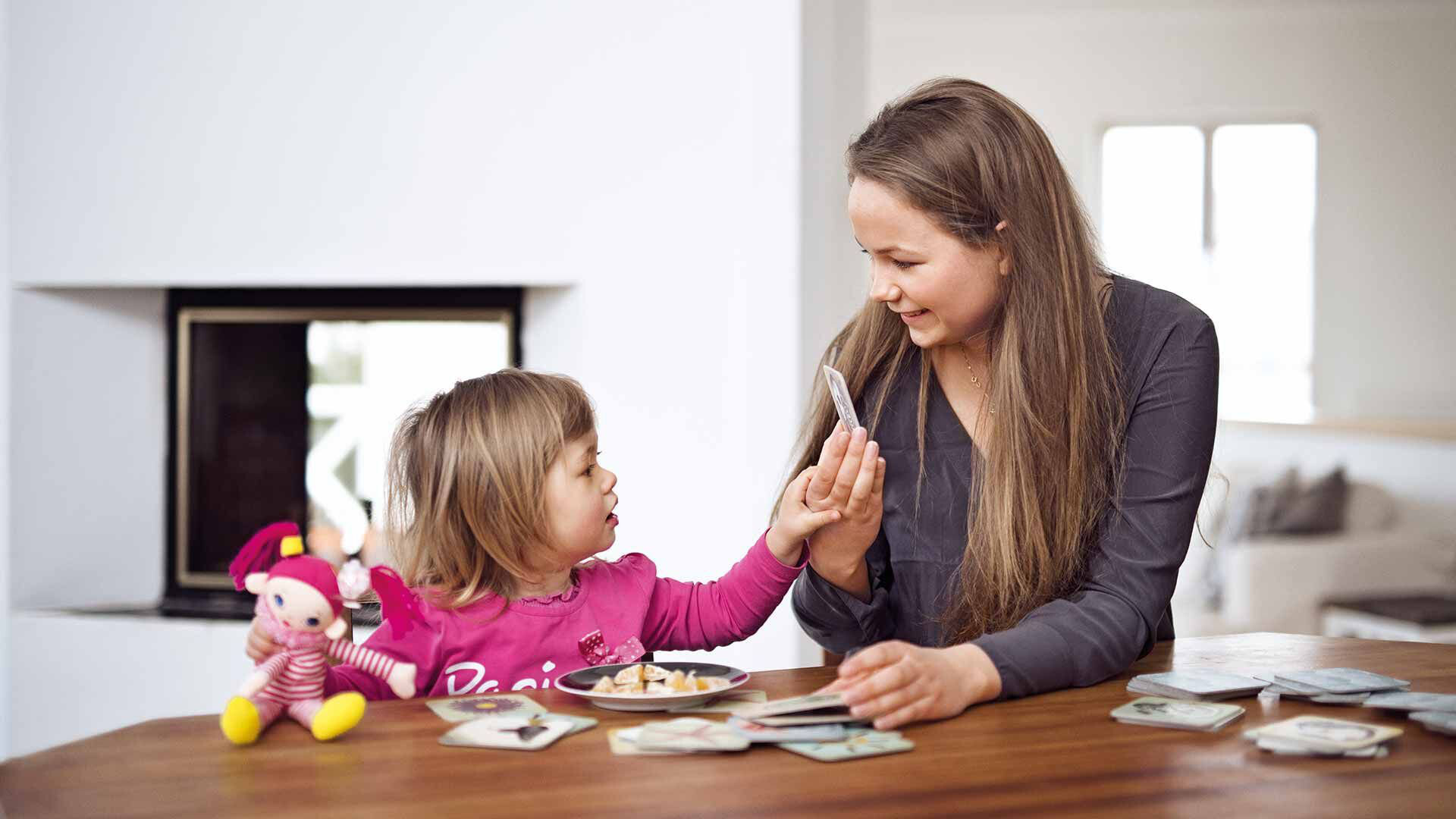 Schimmelhemmend wie ein Kalkputz Mutter und Tochter am Tisch beim Kartenspielen mit weißem Innenputz im Hintergrund