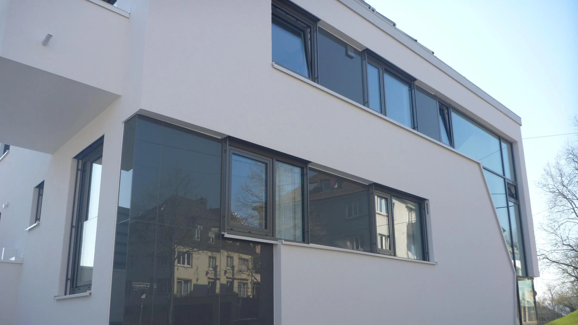 Detailaufnahme der Mischfassade eines Mehrfamilienhauses aus Glas und Putz