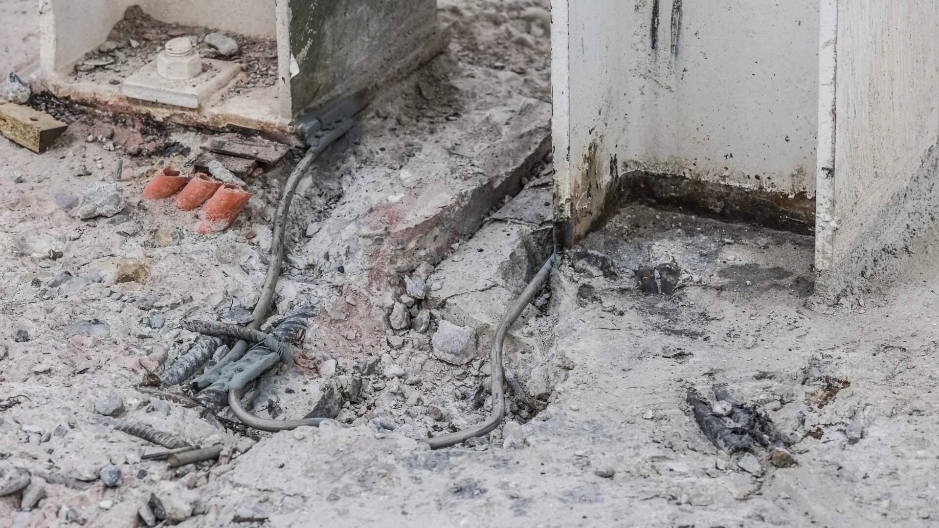 Nahaufnahme eines sanierungsbedürftigen Betonbodens mit freigelegten Kabeln