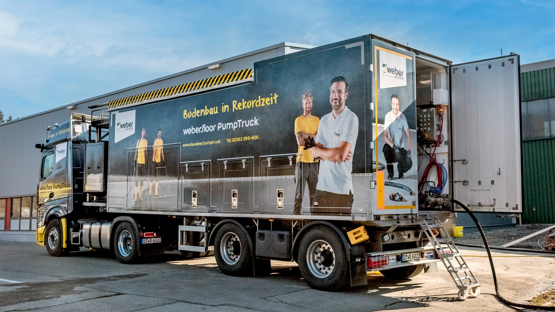Aufnahme des weber.floor PumpTrucks seitlich von hinten, das fahrerhaus ist in der linken bildhäfte, rechts sieht man eine geöffnete tür, da kommt der schlauch heraus 