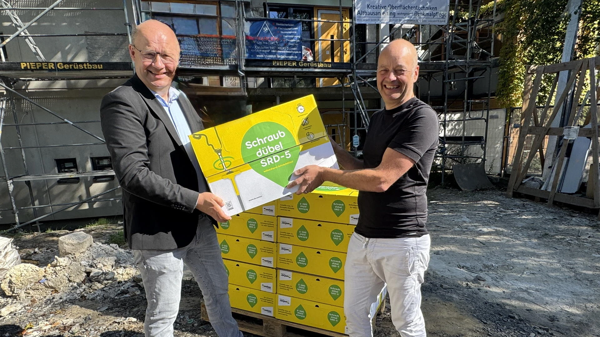 Georg Kolbe, Leiter Produktmarketing Putz- und Fassadensysteme, (links) gratuliert Frank Vorwerk zum Einbau des 100 Millionsten WDVS-Dübels von Saint-Gobain Weber