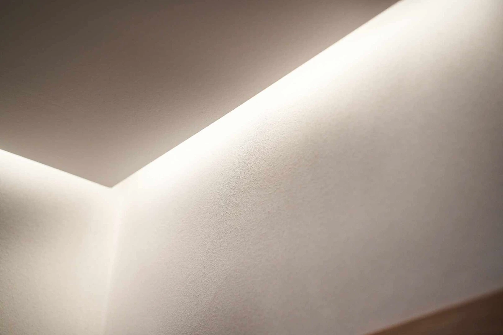 Detailaufnahme der Ecke zwischen den Wänden und der Decke im Wohnzimmer mit einer Unterdeckenbeleuchtung