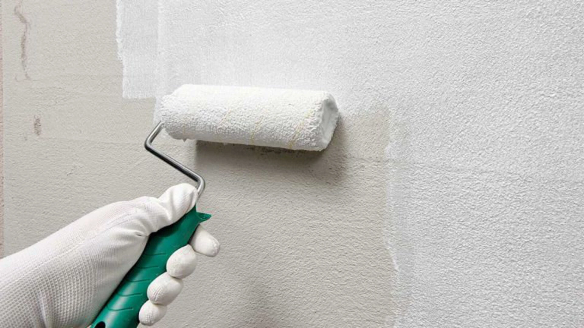 Grundieren einer Wand mit einer weißen Farbrolle 