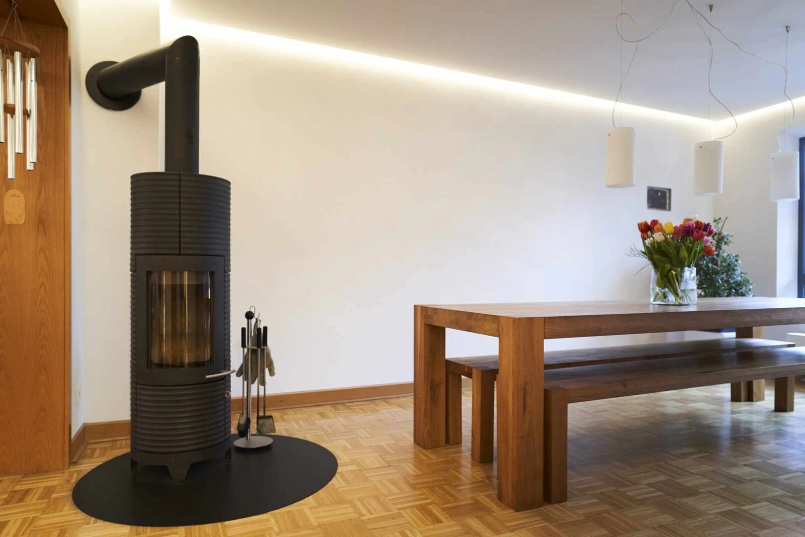 Wohnzimmer mit Holzboden, schwarzem Kamin, Holztisch und weißen, mit Kalkputz verputzten Wänden