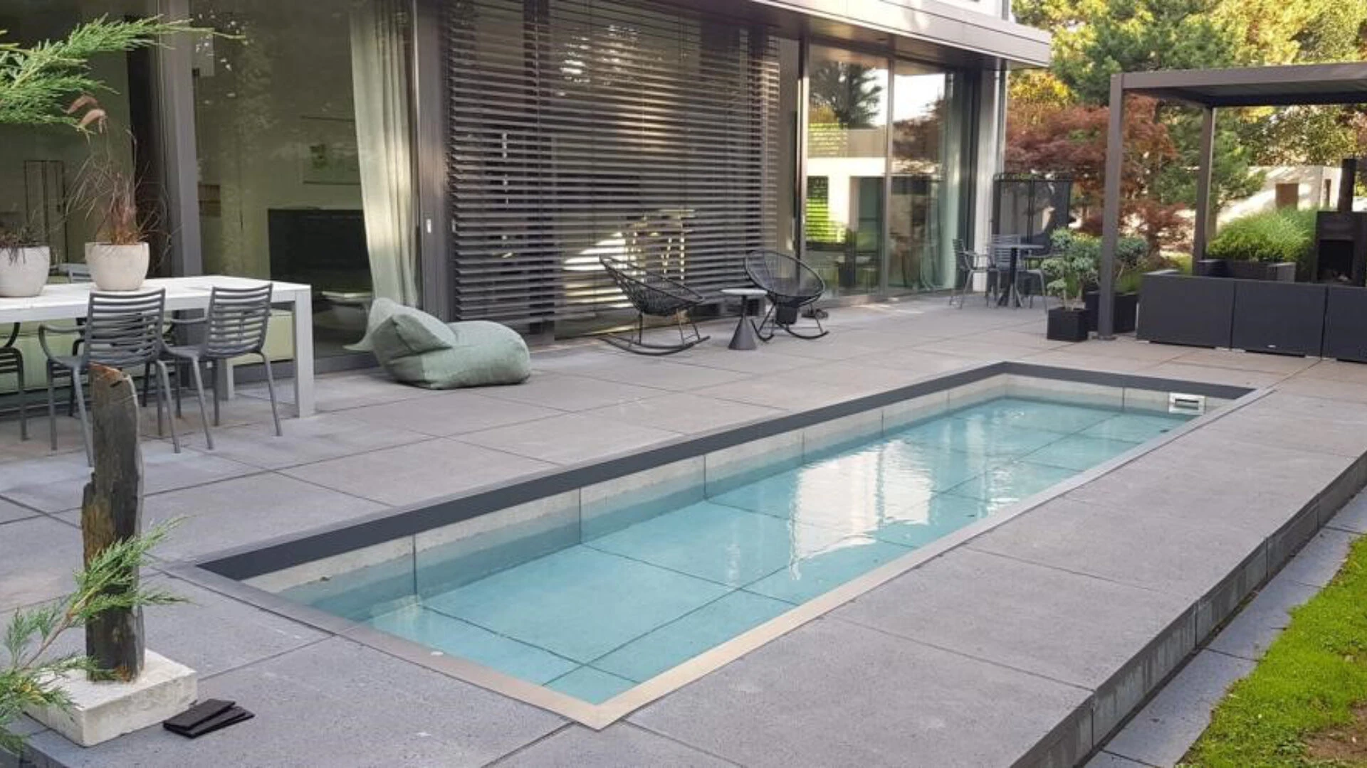 Terrasse eines Privathauses mit Pool und großformatigen Fliesen