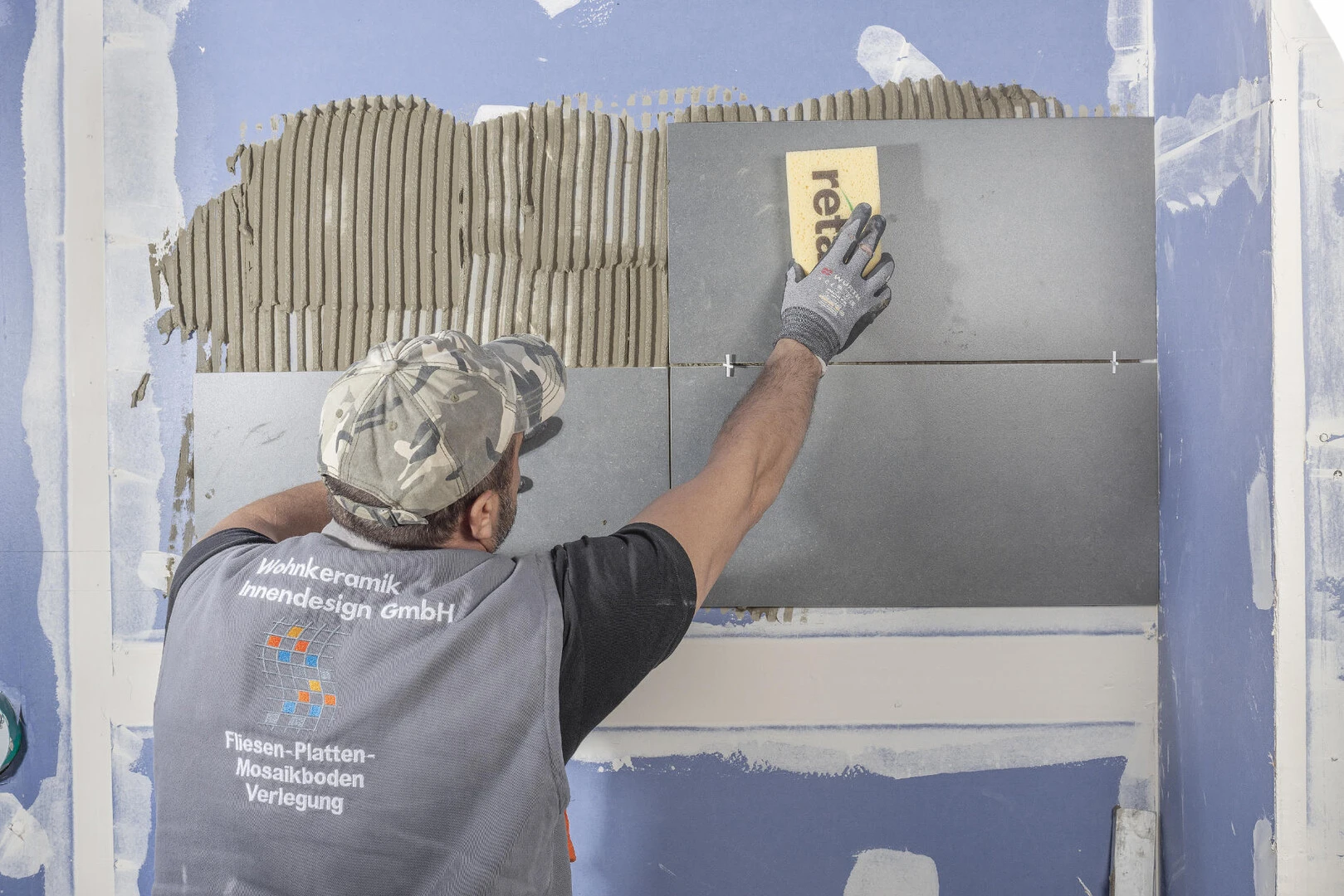 Fachhandwerker verlegt dunkle Fliesen an der Wand mit weber.xerm 844