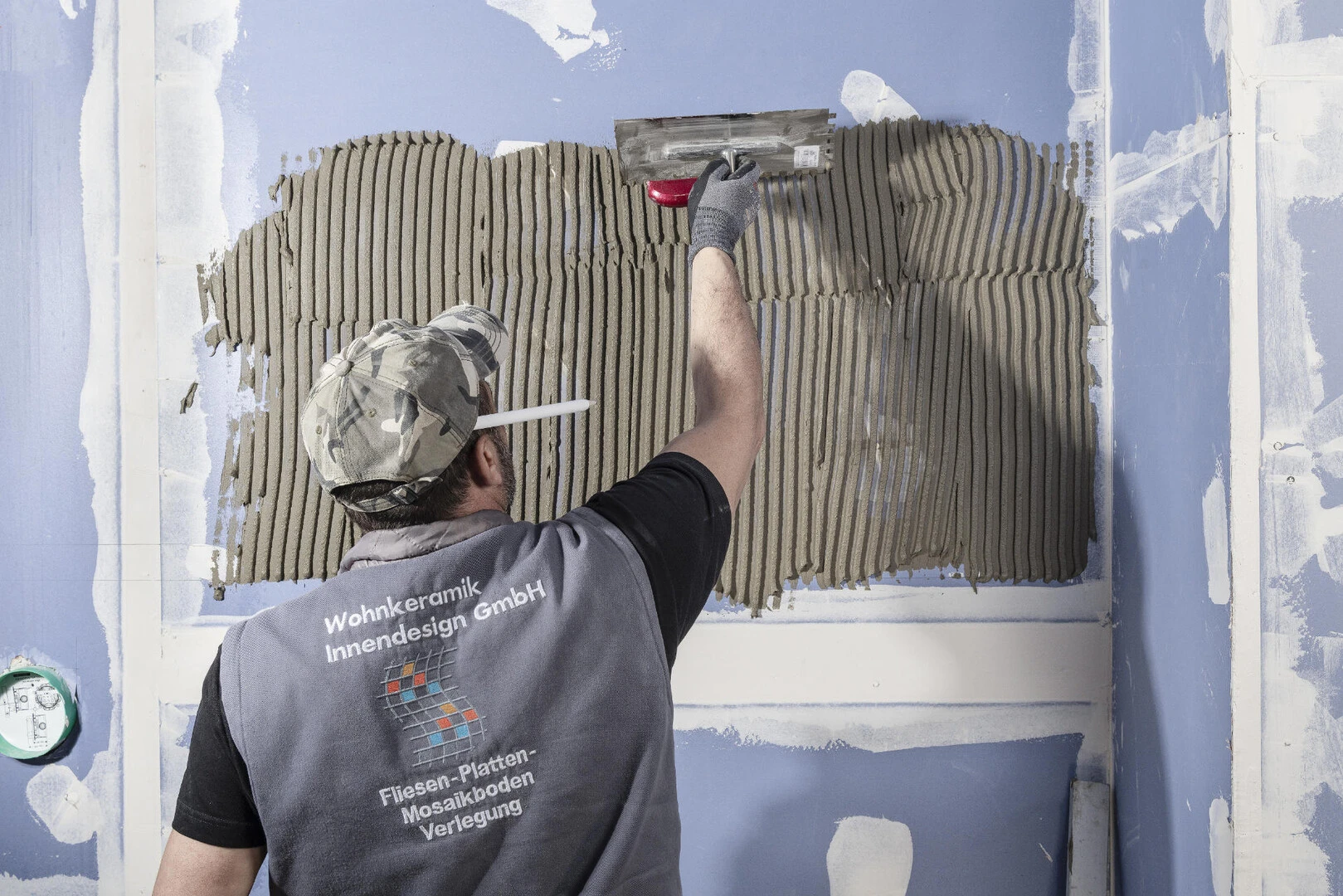 Fachhandwerker zieht Fliesenkleber an der Wand auf