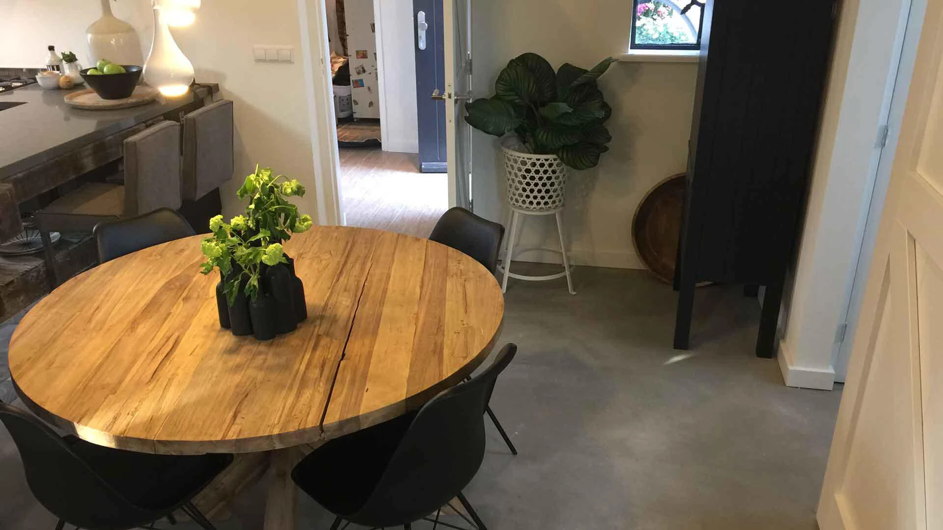 Esszimmer mit rundem Holztisch, Pflanzen und einer hellgelben Wandfarbe