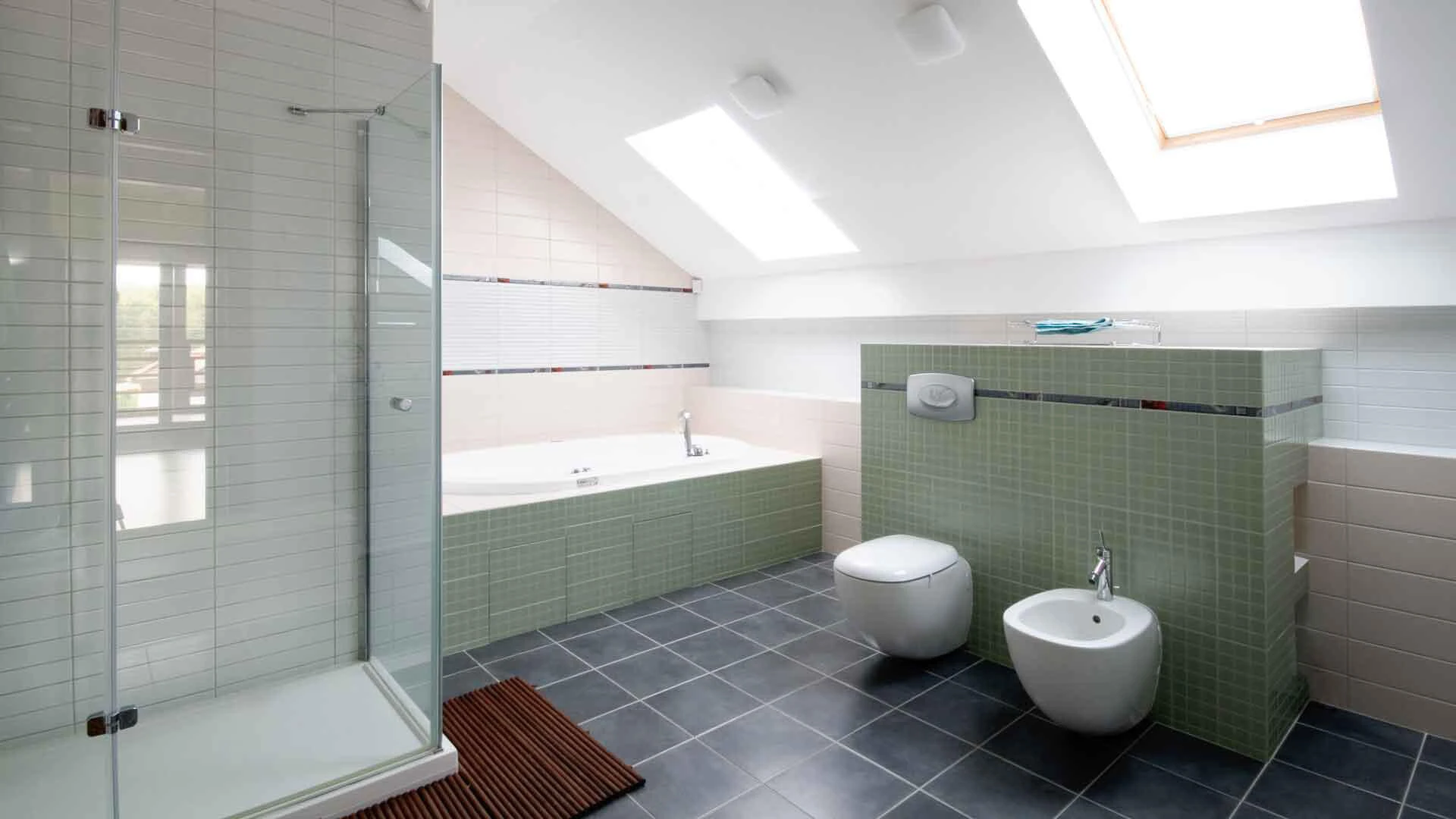 Badezimmer mit weiß gestrichenen Dachschrägen und grün gefliester Einrichtung
