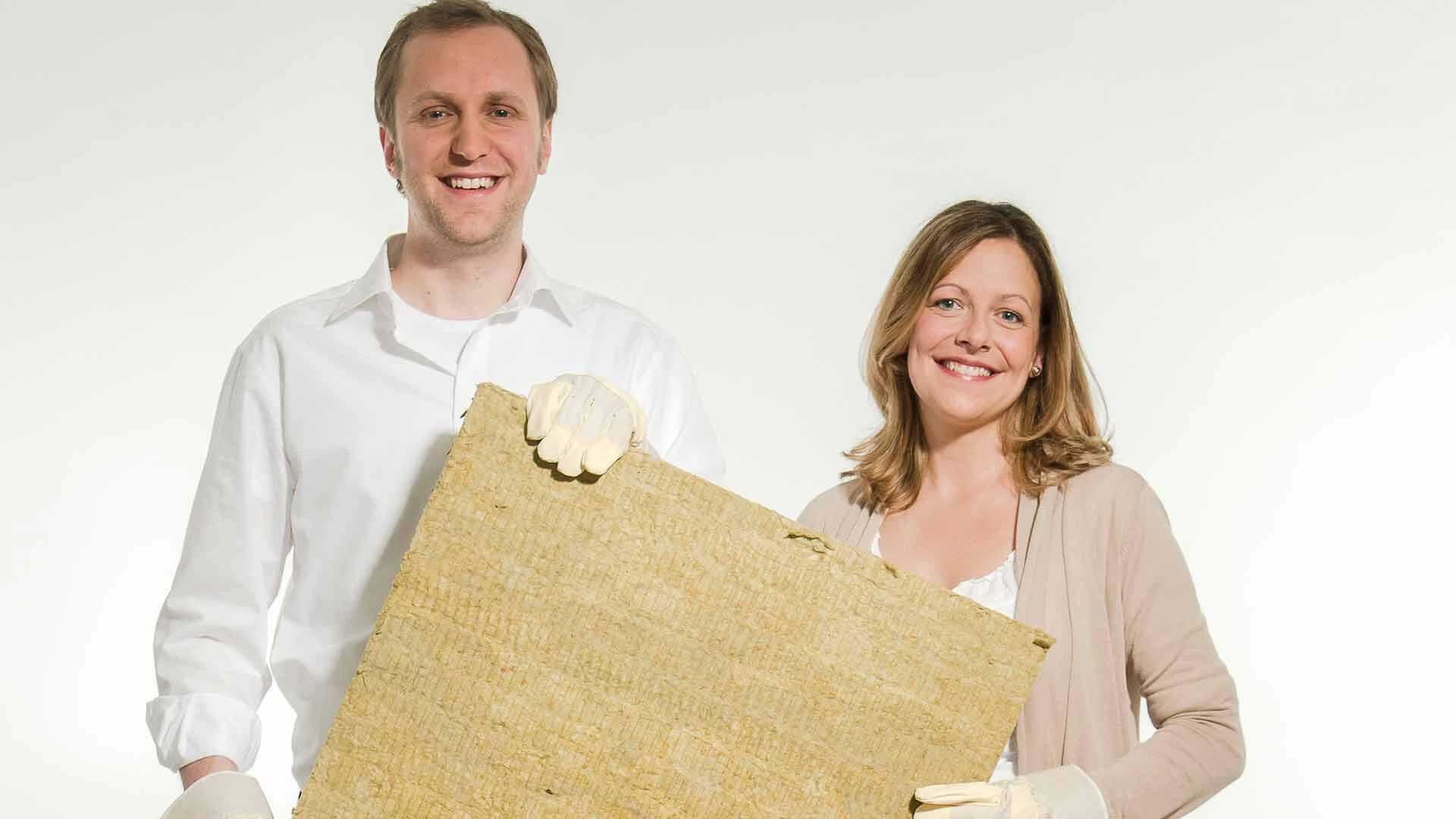 Ein Mann und ein Frau halten eine Dämmplatte aus Mineralwolle fest