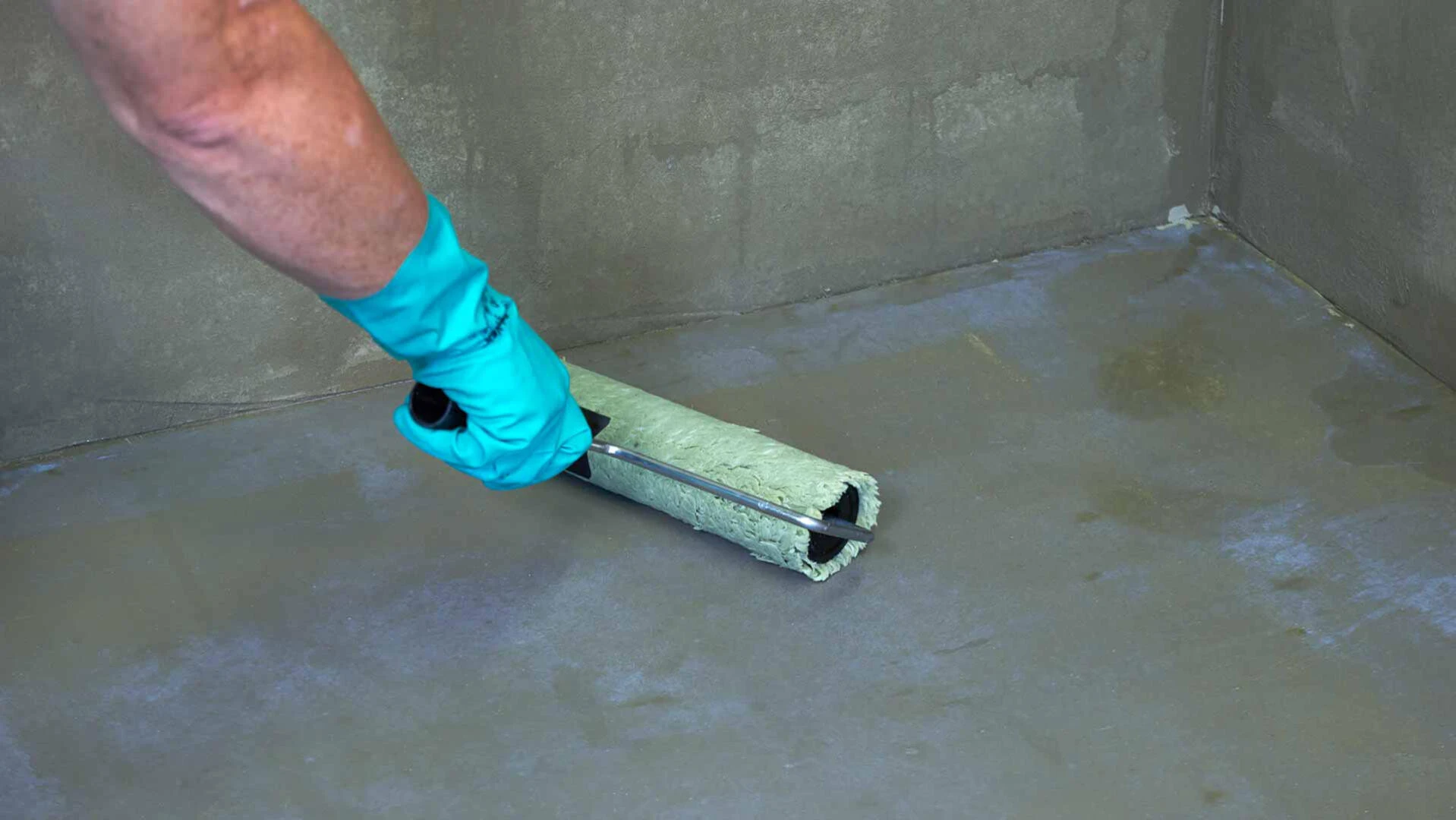 Boden wird mit einer Rolle grundiert, bevor die Fliesen darauf verlegt werden können