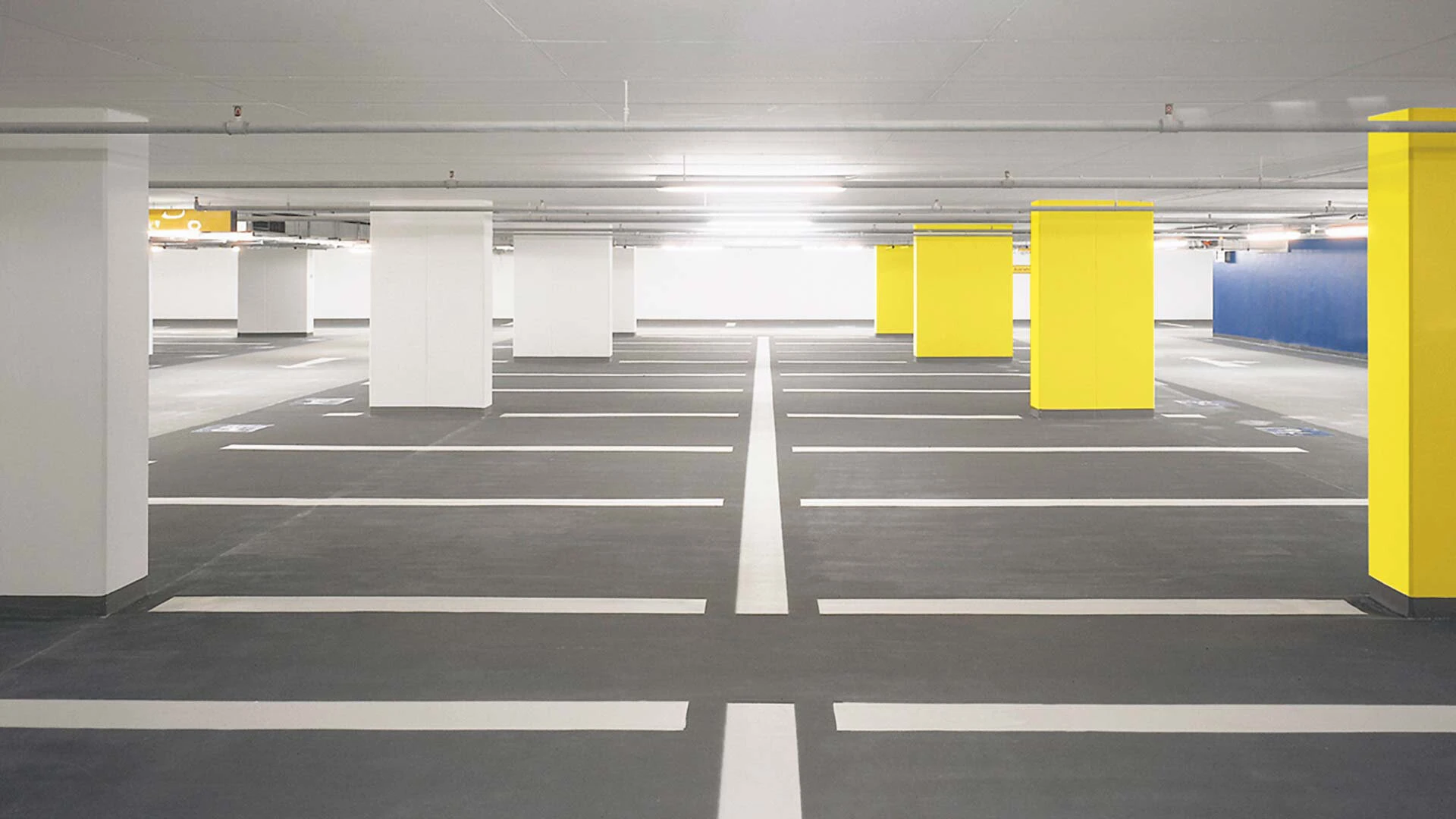Aufnahme einer Tiefgarage mit gelben und weißen Säulen und Parktaschen auf Industrieboden