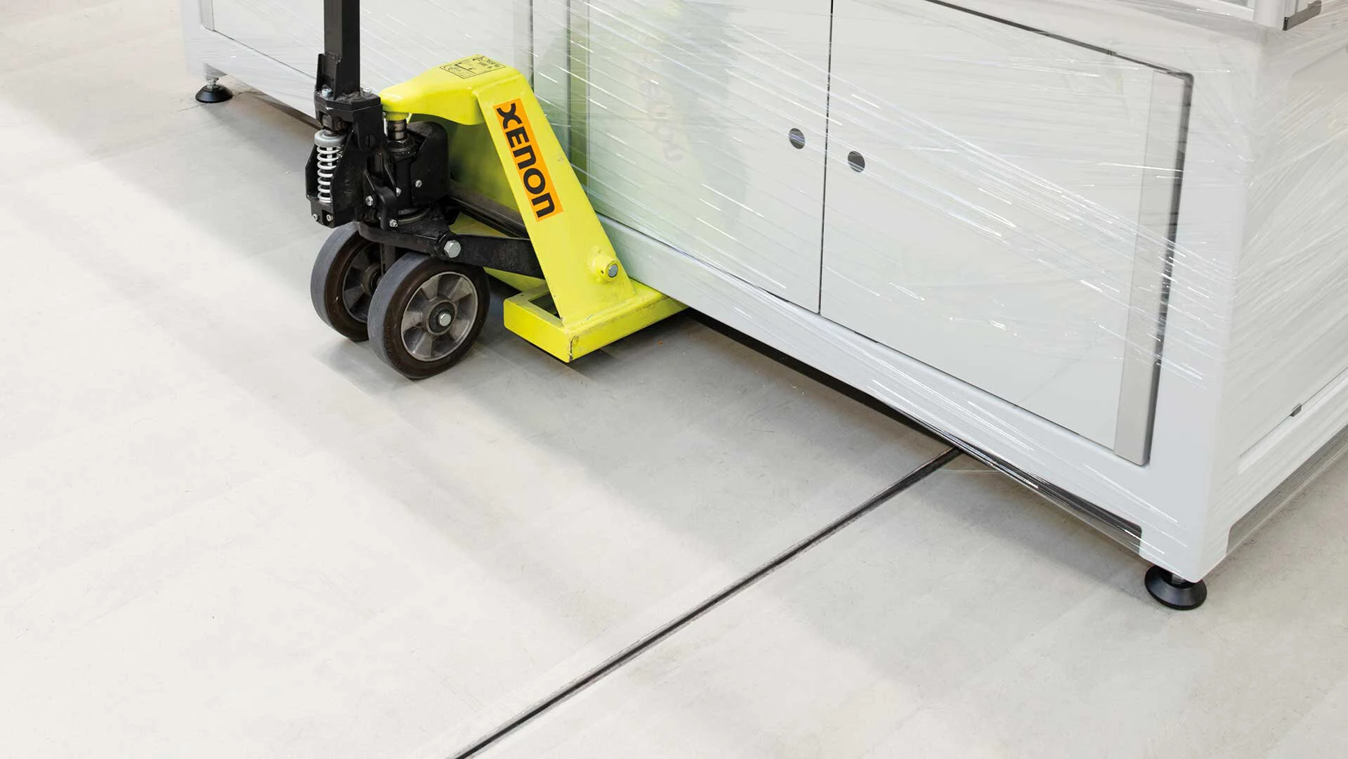 Kommode wird mit einem Hubwagen über einen Industrieboden transportiert