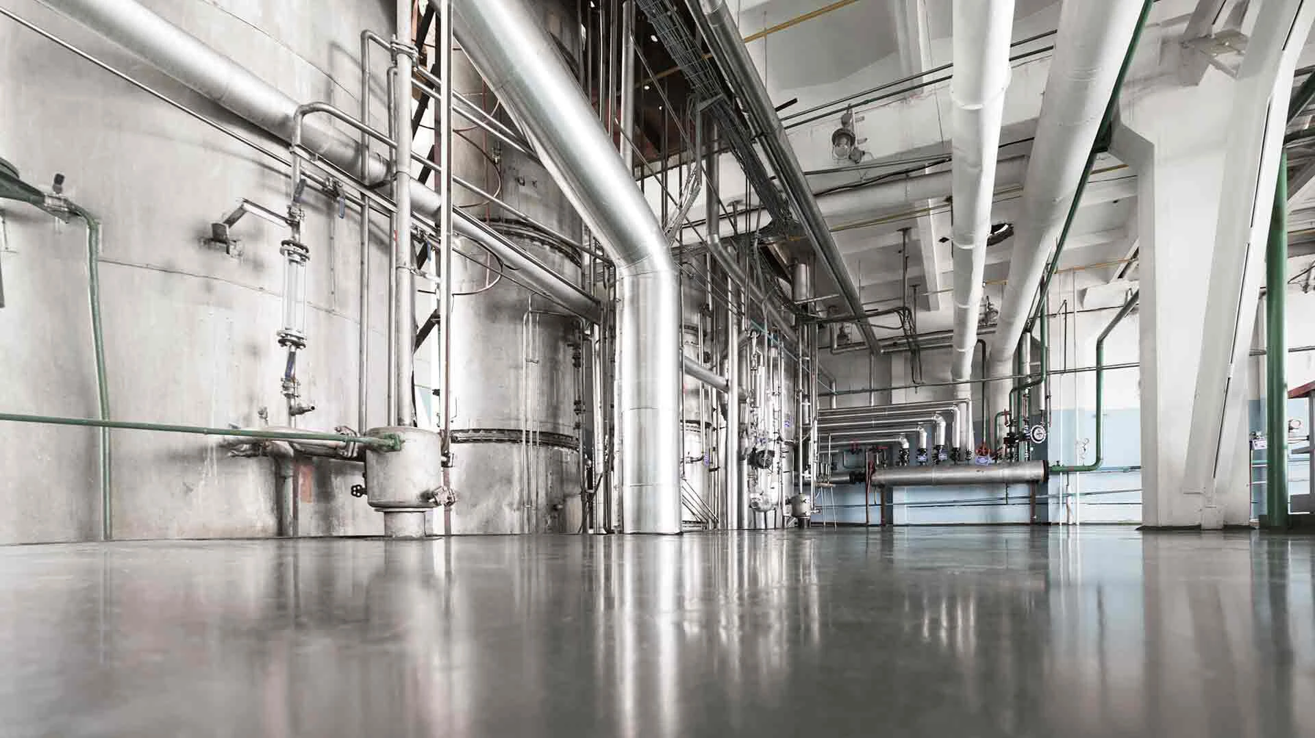 Leere Industriehalle mit grauen Rohren an den Wänden und einem grauen Industrieboden