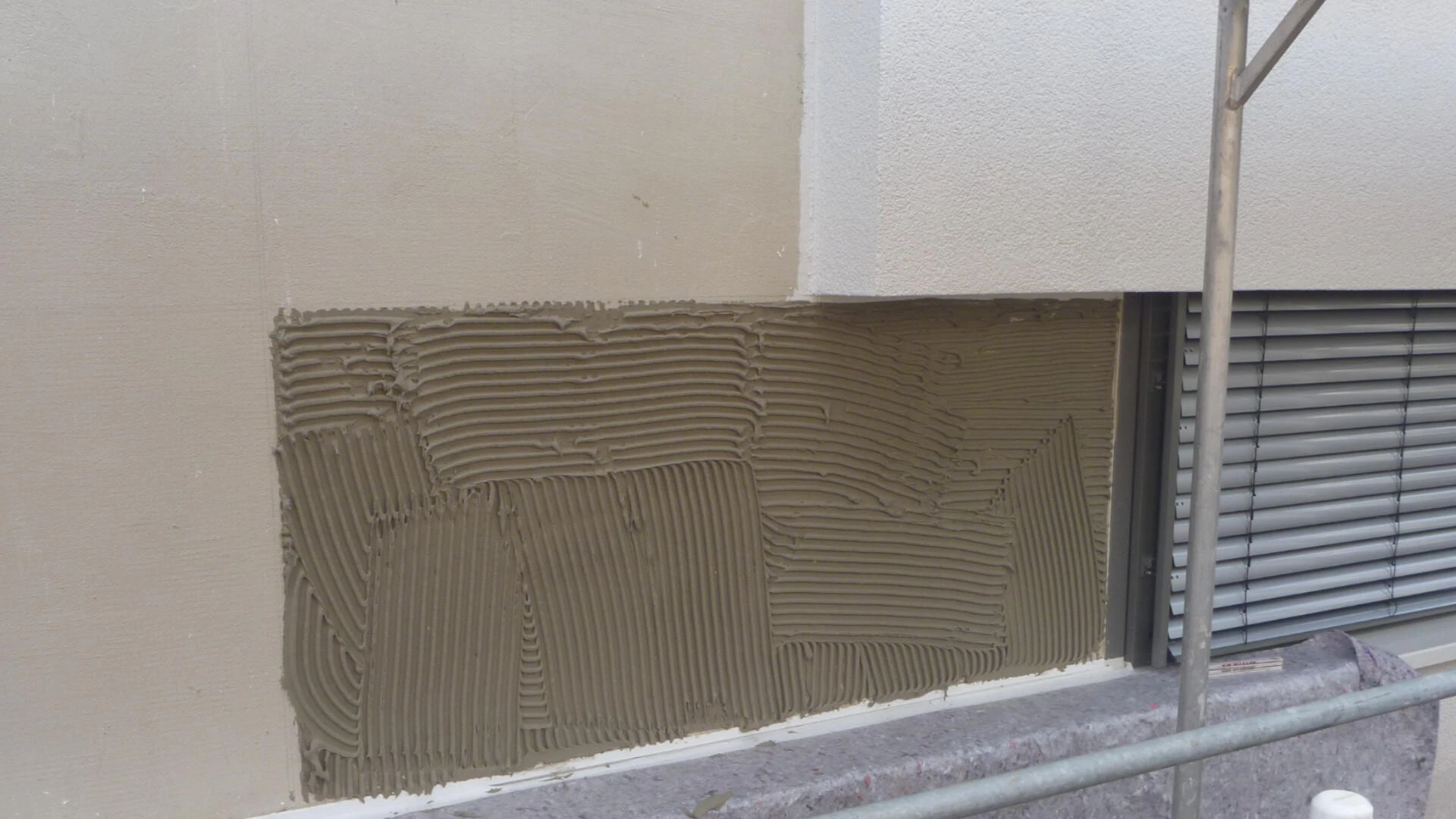 Detailaufnahme der Mischfassade mit einem frischen Kleberbett für eine Glasplatte