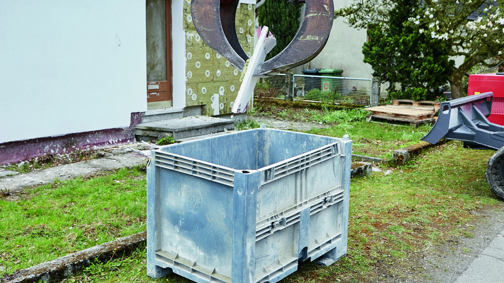 Putzschicht wird von Bagger in Container entsorgt
