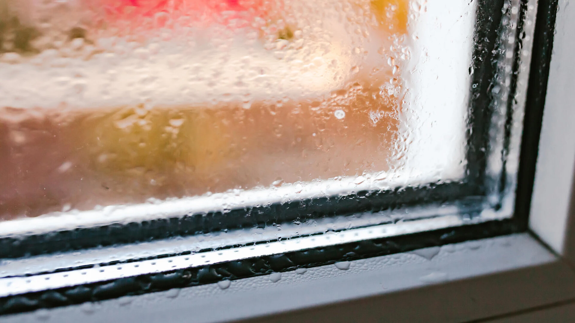 Detailaufnahme einer Ecke von einem feuchten Fenster, wo auf dem Fensterrahmen Tropfen sind