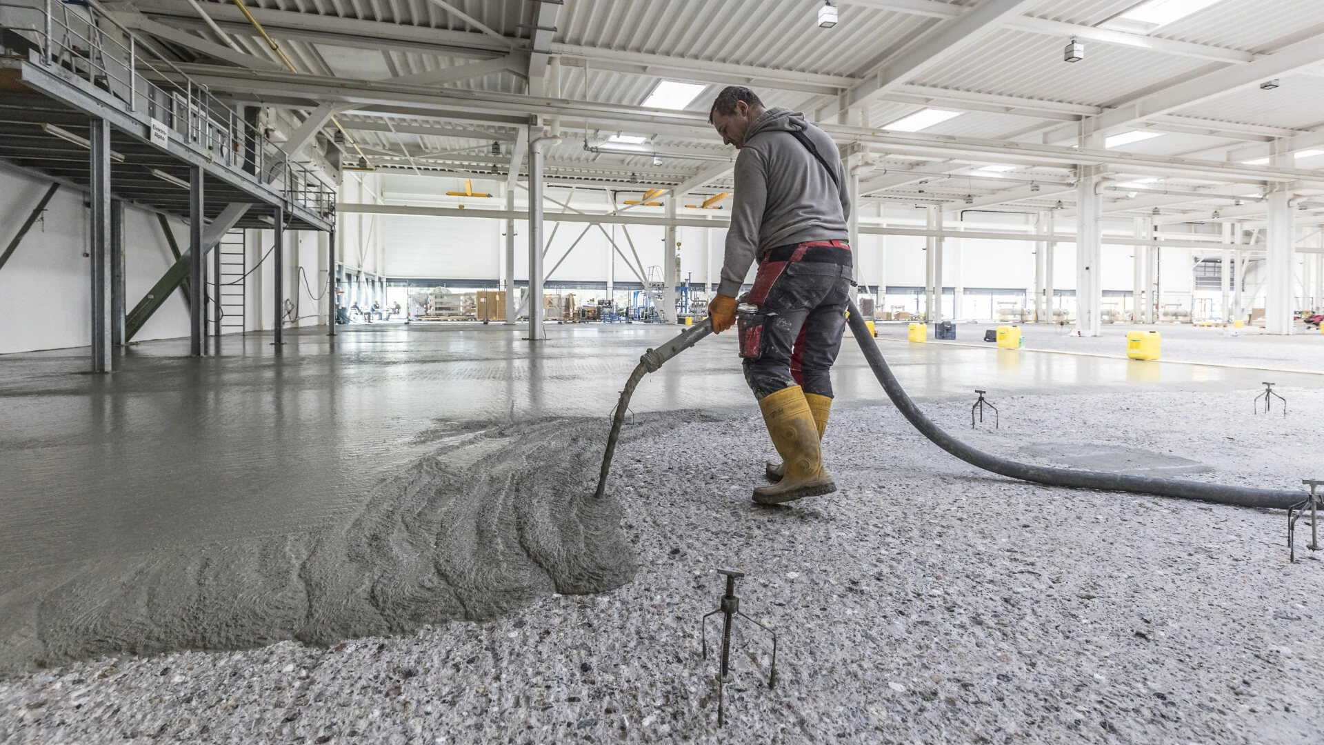 Betonersatzmörtel wird aus einem Schlauch auf eine große Industriefläche gepumpt