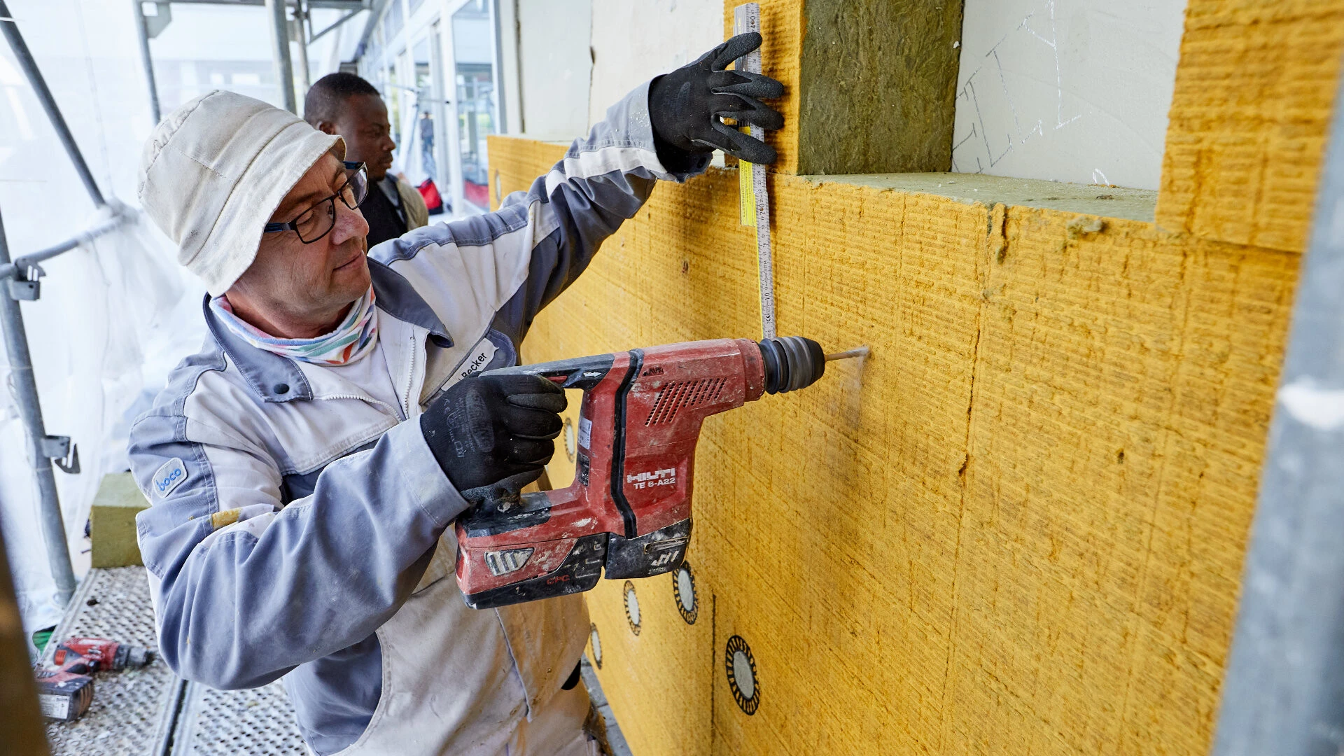 Handwerker befestigt WDVS Platten des weber.therm circle an einer Fassade.