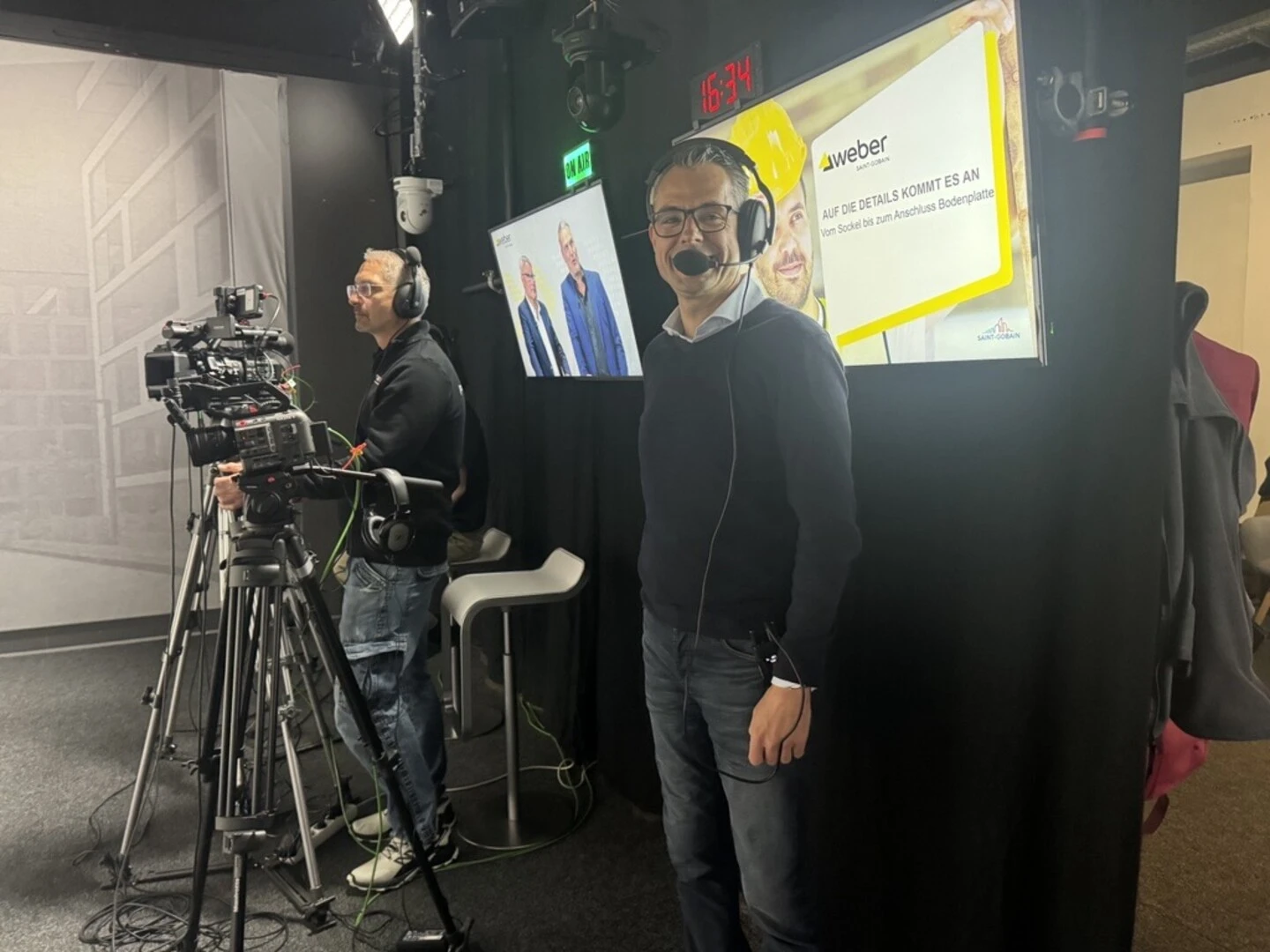 Aufnahme eines Kamerateams in einem Studio mit professioneller Licht‑ und Aufnahmetechnik. Monitore im Hintergrund zeigen Inhalte einer Weber‑Präsentation mit gelbem Design