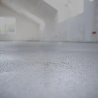 Nahaufnahme eines Estrichs in einem Rohbau, der Hintergrund ist sehr unscharf, der Fokzs liegt auf der Texture in der Mitte des Bildes