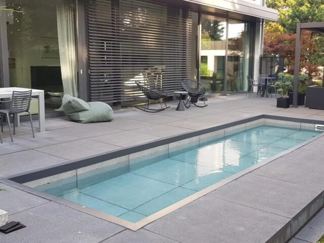 Terrasse eines Privathauses mit Pool und großformatigen Fliesen