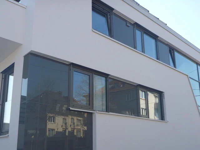 Detailaufnahme der Mischfassade eines Mehrfamilienhauses aus Glas und Putz