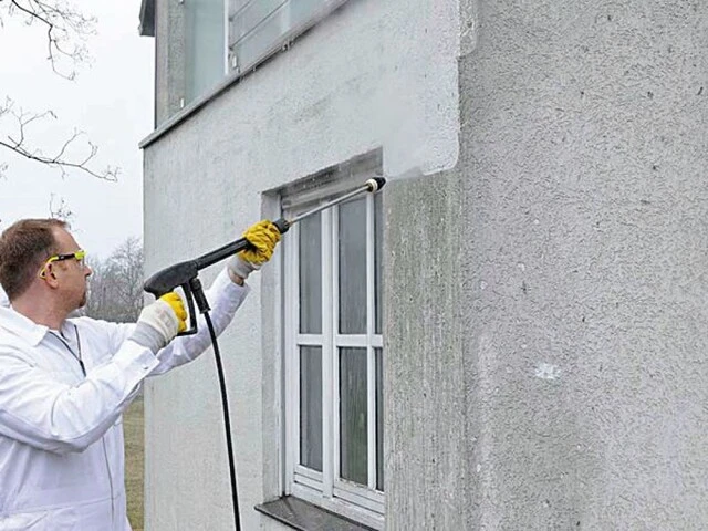 Mann reinigt die Fassade mit einem Hochdruckreiniger, um Putzfassade sanieren zu können