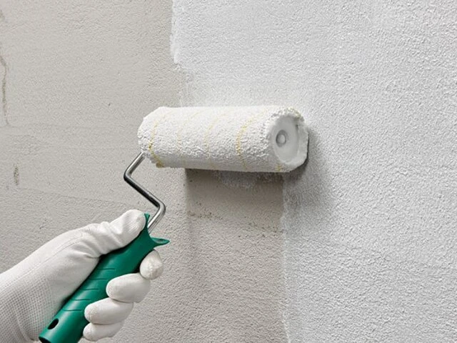 Scheibenputz wird mit einer Putzwalze an der Wand aufgetragen