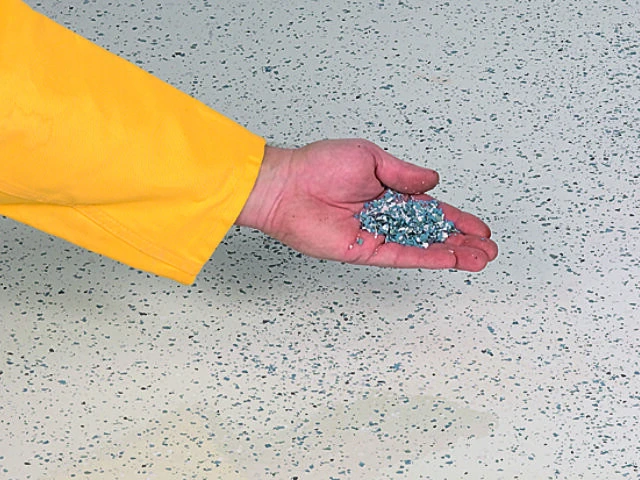 Hand streut blaue und weiße Farbchips auf den Untergrund