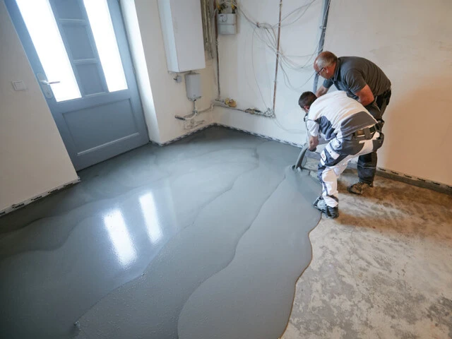 Blick in einen Kellerraum, in dem zwei Handwerker Dichtspachtel frisch in frisch ineinander gießen