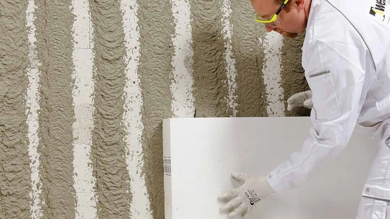 Handwerker bringt Dämmplatte an der Wand an