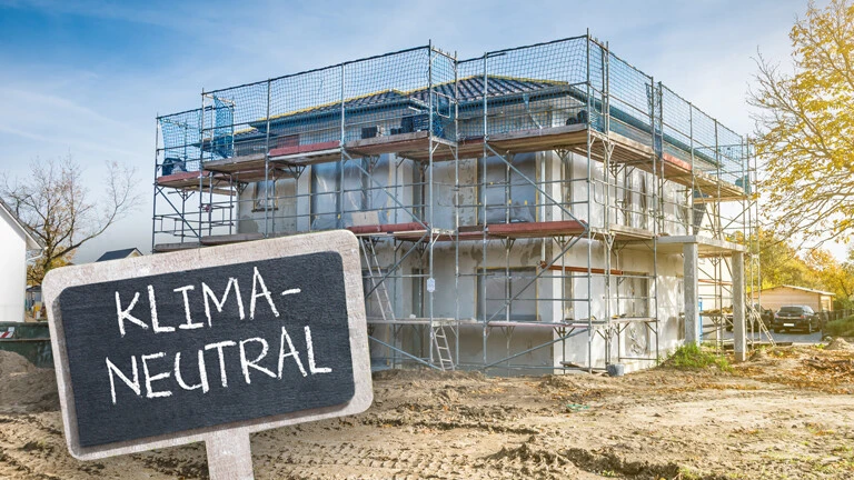 Gebäude mit Baugerüst drum herum, wo ein Schild mit der Aufschrift Klimaneutral vor steht