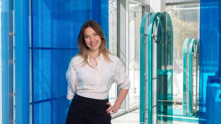 Junge Frau mit weißer Bluse vor blauer Glaswand