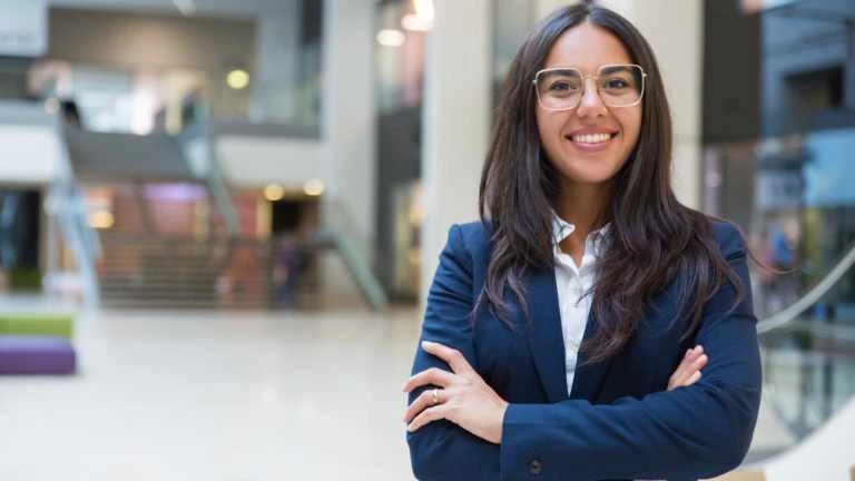 Junge Frau mit Brille und blauem Blazer in einem Bürogebäude