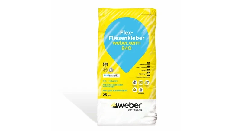 Gelber Foliensack mit türkiesem Tropfen auf dem Flex-Fliesenkleber weber.xerm 840 steht