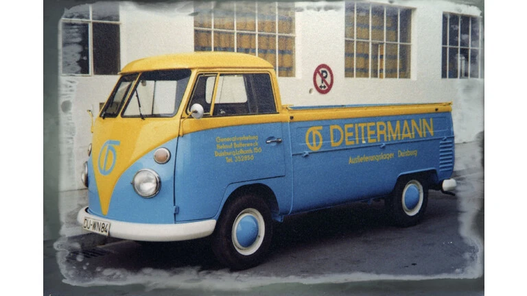 Alter VW Bulli in Deitermann-Farben Hellblau und Gelb mit Deitermann Logo auf der Seite